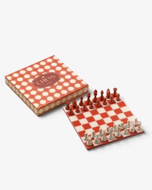 Red and white chess set on a checkered board beside a patterned box.