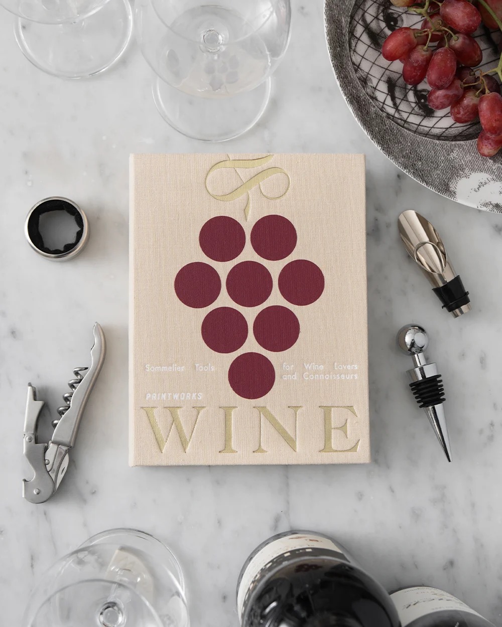 Image 199 - New Trend Flat lay of a beige wine book titled 'WINE' with a grape cluster illustration, surrounded by wine accessories on a marble surface.