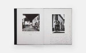 Open photo book with two black-and-white images: a nighttime street scene on the left showing a couple walking, and a couple in a hallway on the right, with handwritten captions around both images.