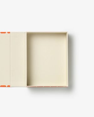 Open rectangular cream-colored box with lid lifted, revealing beige interior and orange corner accents (top-down view).