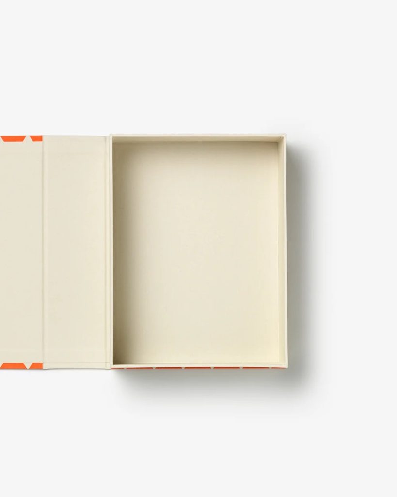 Open rectangular cream-colored box with lid lifted, revealing beige interior and orange corner accents (top-down view).