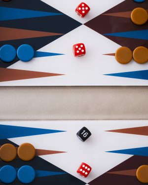 Two red dice resting on a white diamond of a geometric board, surrounded by blue and orange game pieces on a color-blocked background.