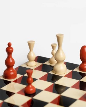 Chessboard with red and natural wood chessmen arranged on a black-and-cream checkered board, viewed from low angle.