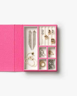 Open pink jewelry box with multiple compartments displaying earrings, rings, and bracelets in silver and gold tones.
