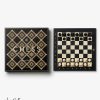 Luxurious black and gold chess set with a geometric diamond-pattern box; board beside shows starting positions of black and white pieces.