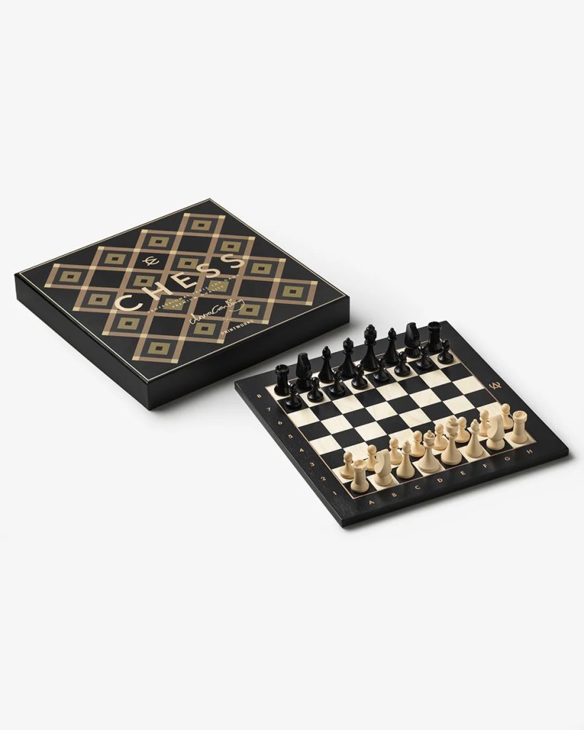 Chess set with a black and beige board and matching wooden pieces, displayed beside a decorative black box with a geometric pattern.