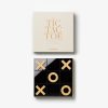Cream-colored box with 'TIC TAC TOE' text on the lid; below it a black tic-tac-toe board with gold X and O game pieces visible.