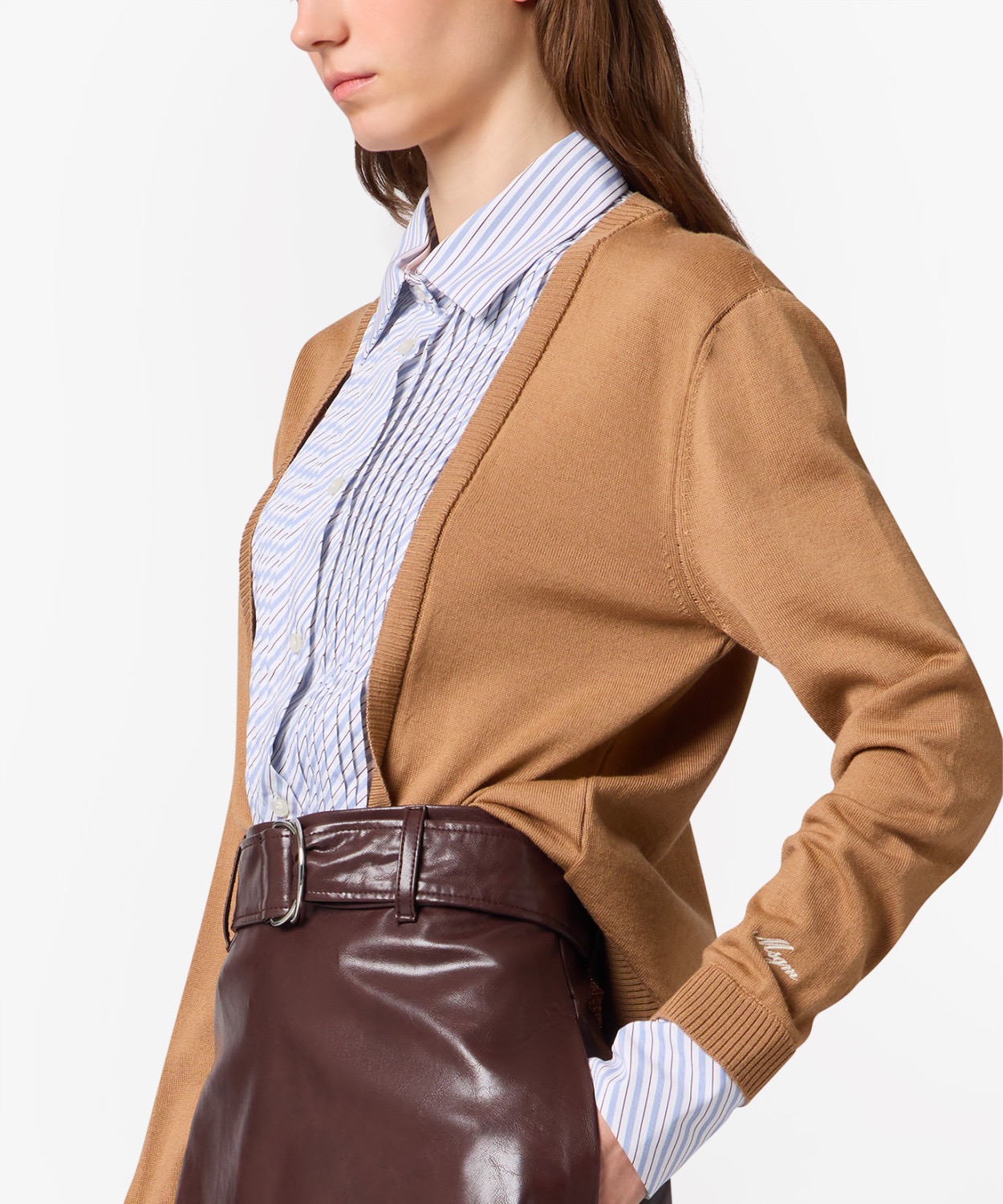 Image 252 - New Trend Side view of a woman in a camel cardigan over a blue striped button-down shirt, tucked into a dark burgundy leather skirt with a belt.