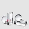 Three transparent glass objects: a sphere on the left, a tall rectangular prism with a pink accent, and a sphere resting on a rectangular base to the right, all on a light gray background.