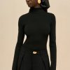 Image 404 - New Trend Portrait of a woman in a black turtleneck and black headscarf with a large gold teardrop earring, looking to the side.