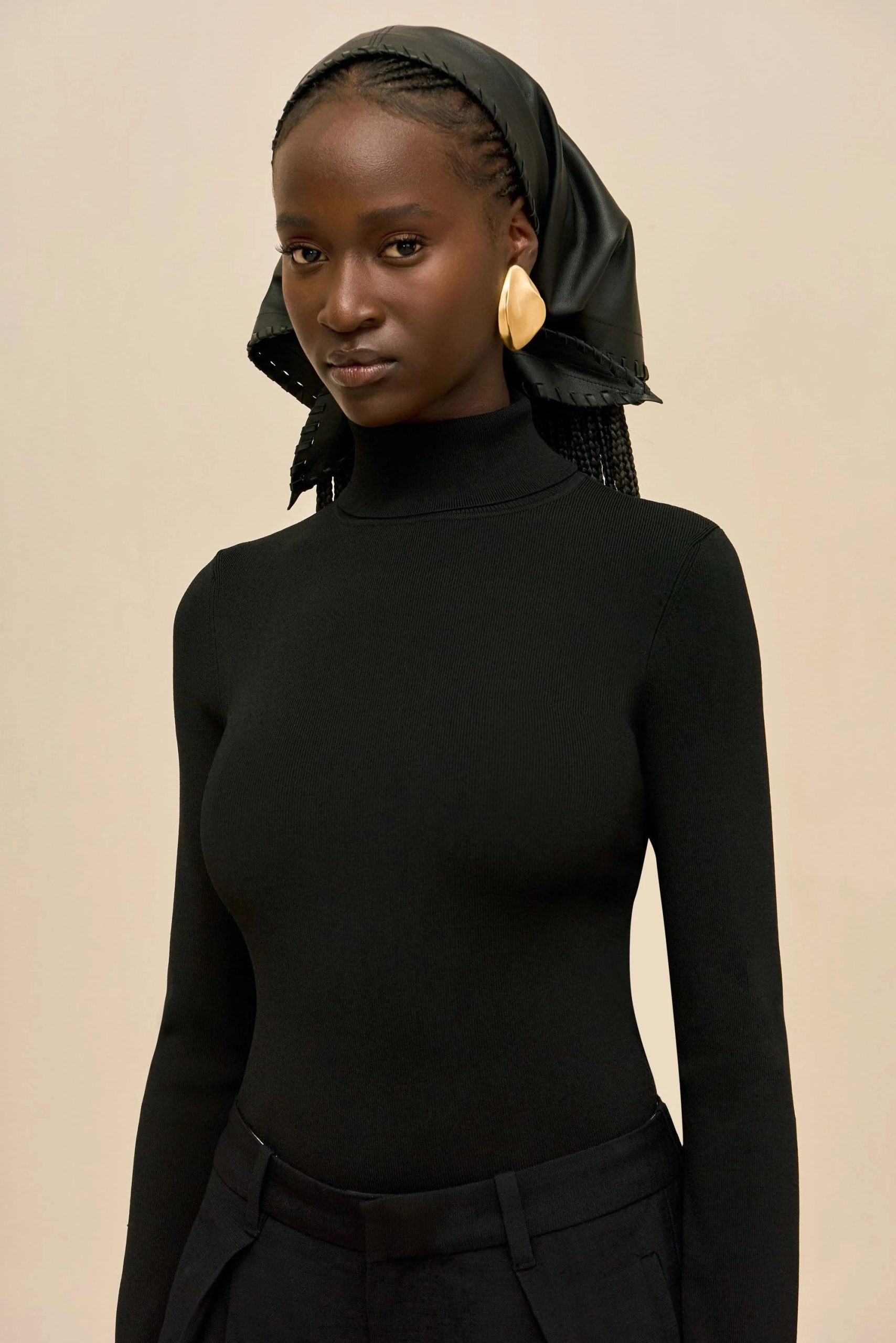 Image 406 - New Trend Portrait of a woman in a black turtleneck with a black headscarf and large gold earrings against a beige background