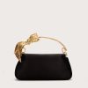 Black handbag with a gold-tone branch/leaf-shaped handle against a light background, product shot for fashion accessory.