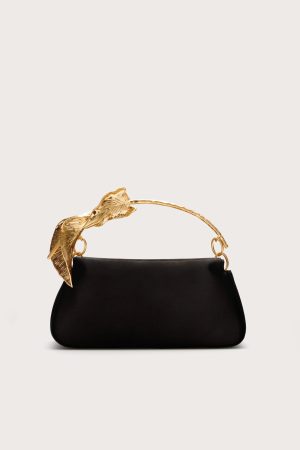 Black handbag with a gold-tone branch/leaf-shaped handle against a light background, product shot for fashion accessory.