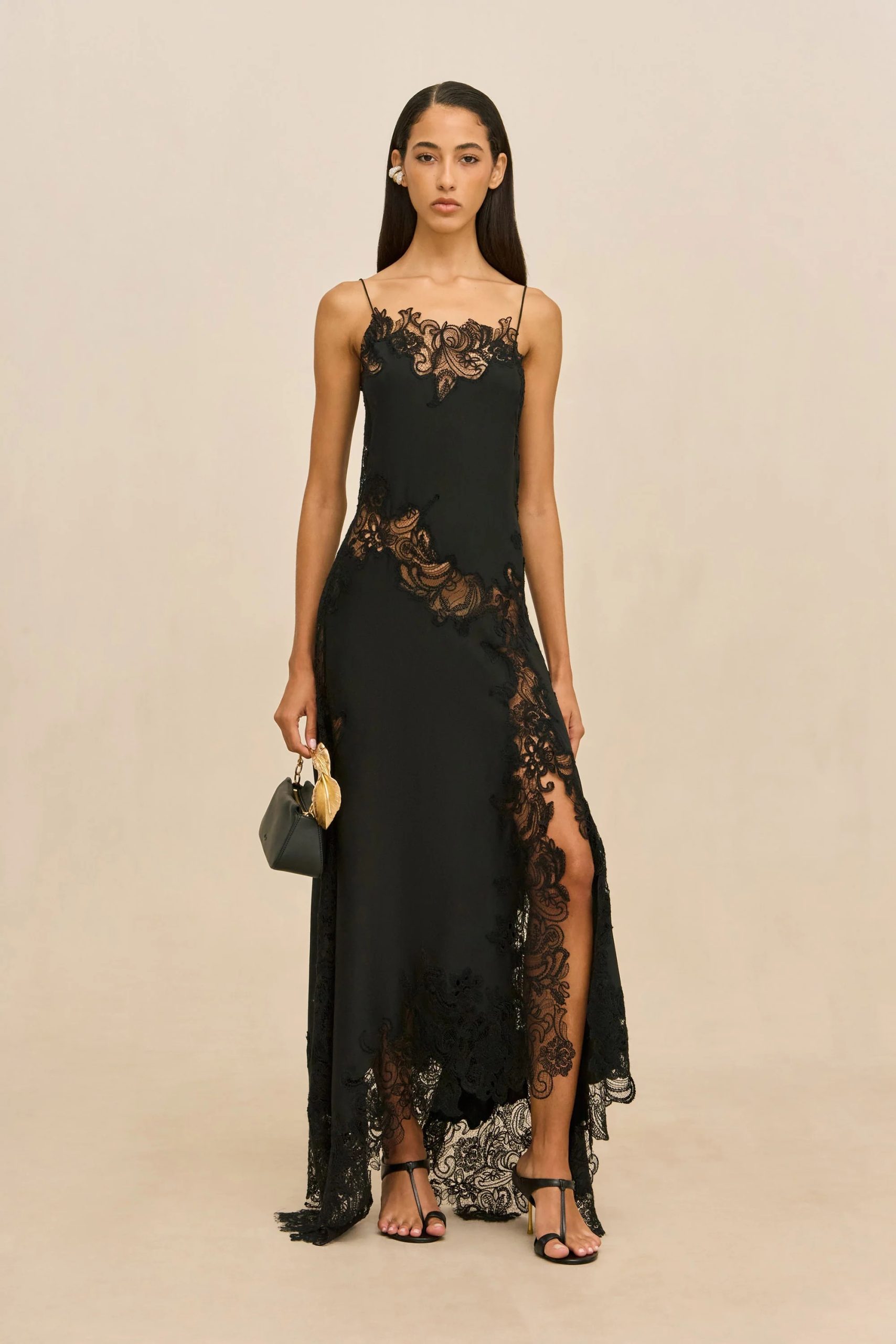 Image 424 - New Trend Woman in a black lace evening gown with spaghetti straps, standing against a beige backdrop