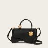 Black leather handbag with gold spherical accents on the handles, set against a light neutral background (crossbody strap visible).
