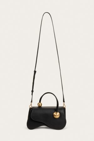 Black handbag with a curved flap and gold spherical hardware hanging from thin straps against a white background
