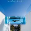 Glass-bottom pool tunnel across a white modern outdoor space; a person swims underwater, with a garden lounge area visible below and the Rizzoli New York logo in the corner.