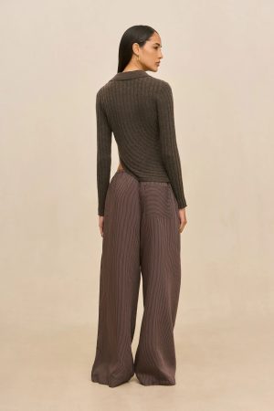 Person standing with back to camera, wearing a brown ribbed knit top and wide-leg striped pants against a neutral backdrop