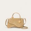 Beige leather handbag with a curved top handle and gold hardware on a light background.