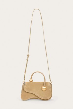 Beige handbag with top handle and long adjustable strap hanging against a light background.