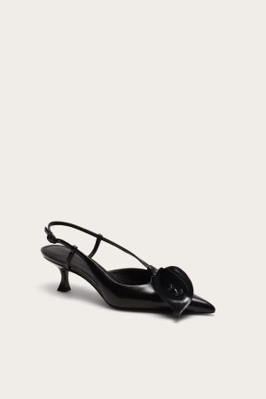 Black strappy high-heeled sandal with a thin ankle strap on a light beige background