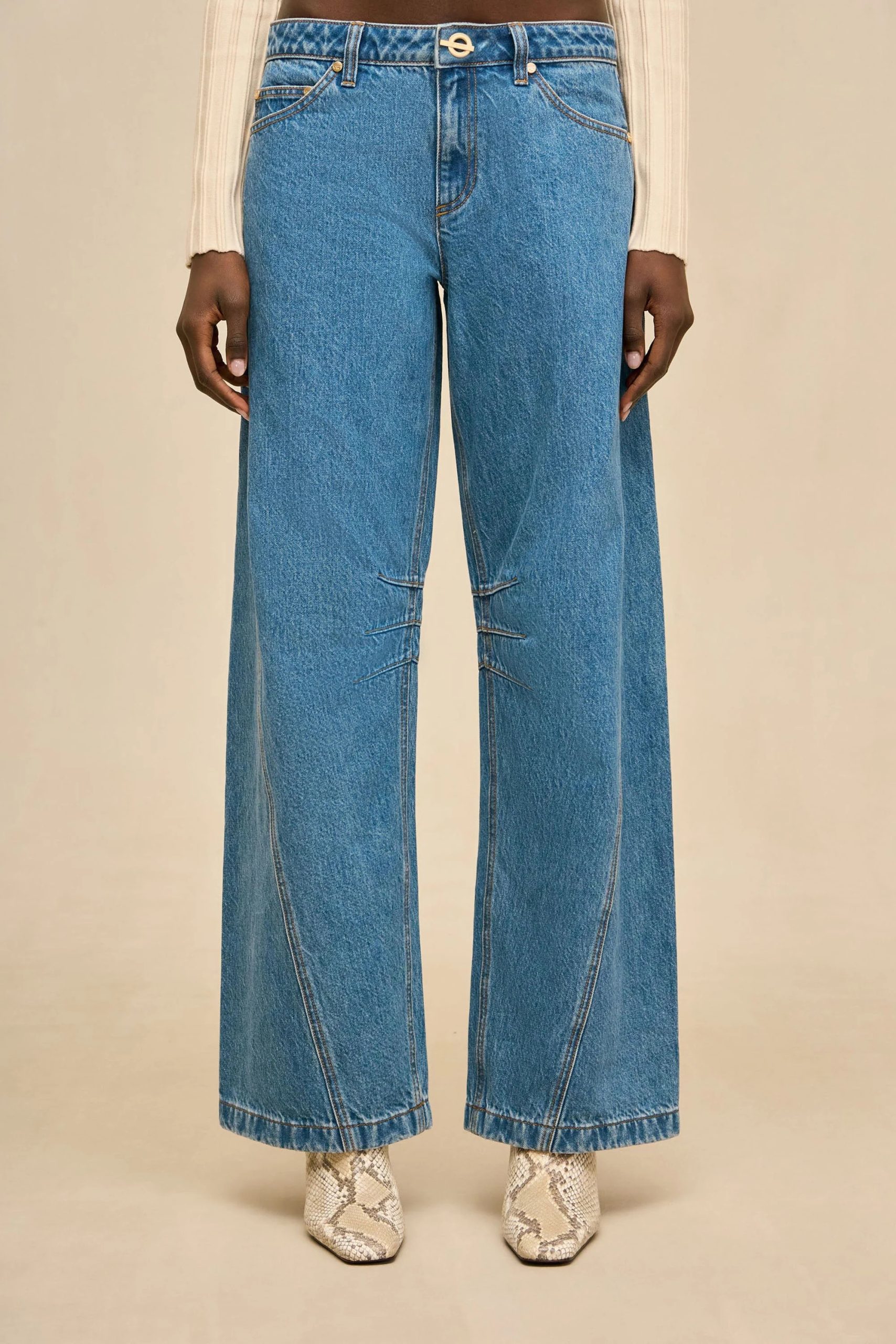 Image 493 - New Trend Model wearing high-waisted blue wide-leg jeans with a beige knit top; snake-print boots visible at the bottom.