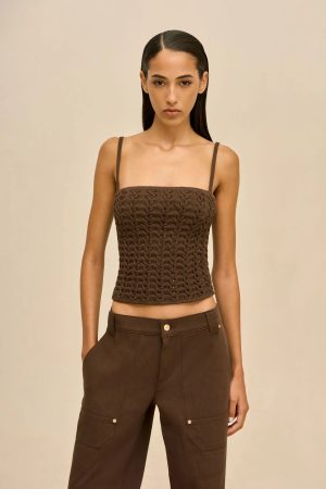 Model wearing a brown braided-knit crop top with thin straps and matching brown cargo pants against a neutral beige background.