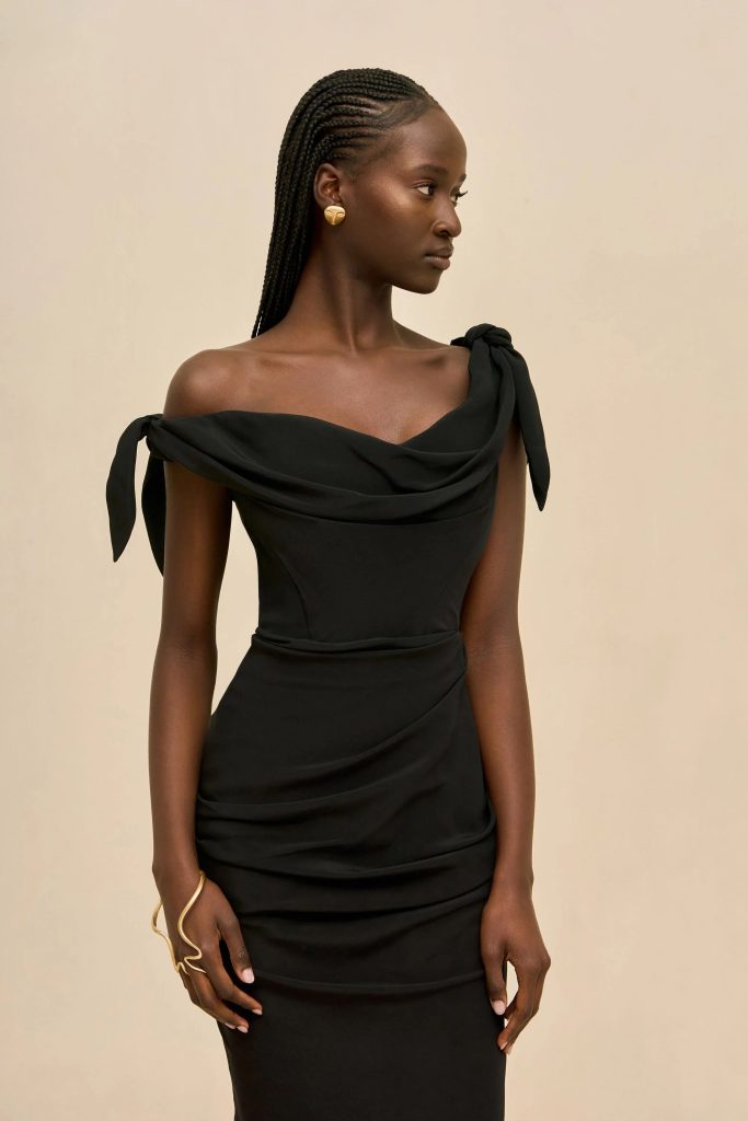 Profile of a Black woman in a black off-the-shoulder dress with braided hair and gold earrings.
