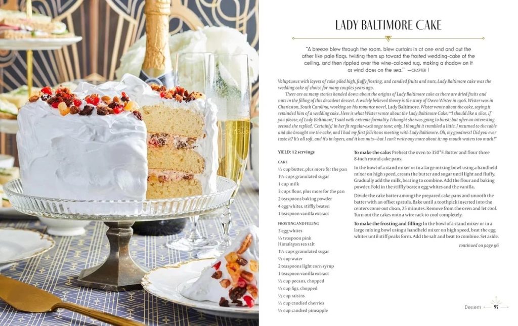 Layered vanilla cake with white frosting and dried fruit on a glass stand, champagne bottle and glass nearby; recipe page titled 'Lady Baltimore Cake' on the right.