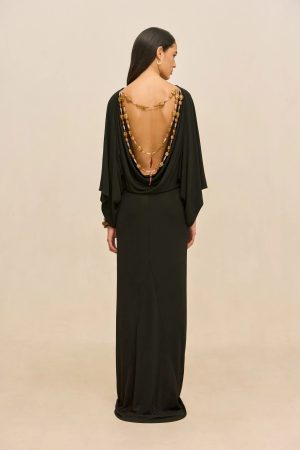 Back view of a woman in a long black gown with a deep open back and layered beaded necklace draping down her back.