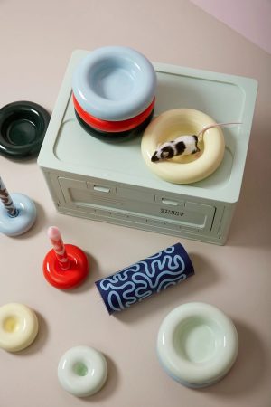 Miniature retro computer with pastel donut-shaped containers stacked on top and a small black-and-white mouse inside a cream donut ring on the side.