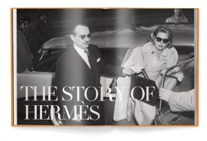 Open magazine spread with a black-and-white photo of a man helping a woman exit a car, overlaid with 'THE STORY OF HERMÈS'.