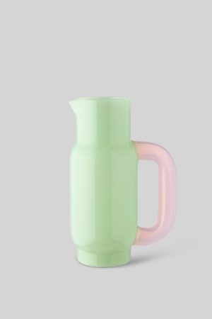 Pastel green pitcher with a pink translucent handle on a gray background for pouring drinks.