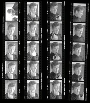 A black-and-white strip of film frames showing a man posing with a mobile phone in various positions, like talking, holding, and thinking, arranged in four vertical columns.