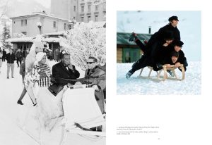 Black-and-white winter scene showing a group riding a decorative sleigh through a snowy town square, with onlookers and a building in the background.