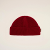 Close-up of a red knit beanie against a pale beige backdrop, showing the top half of the hat.